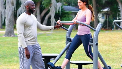 Couple working out on outdoor fitness equipment