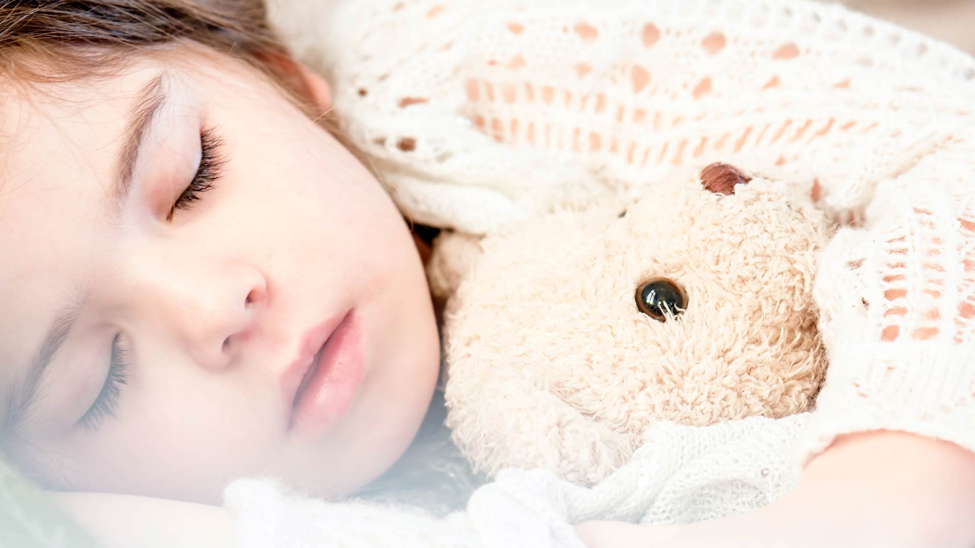 young girls sleeping while holding her teddy bear
