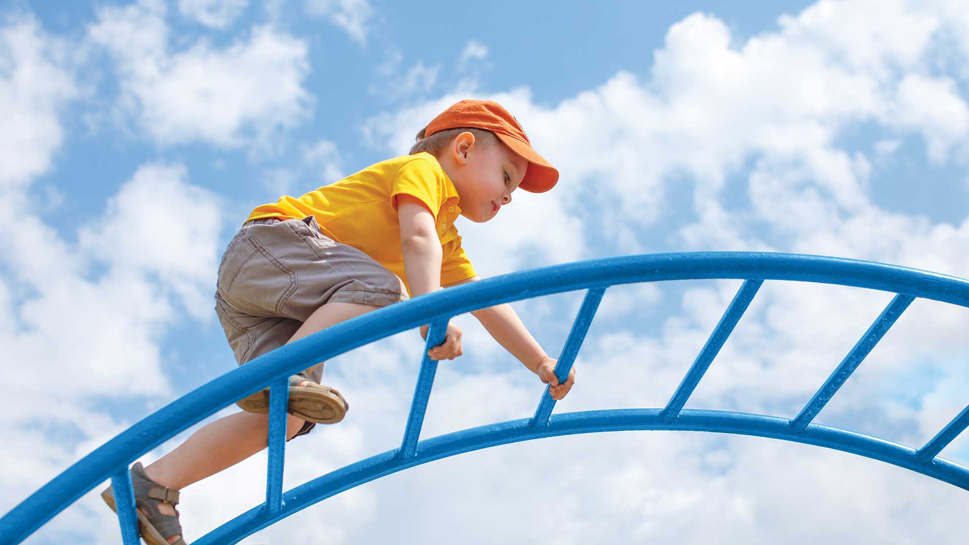 little boy climbing an arch climber playground