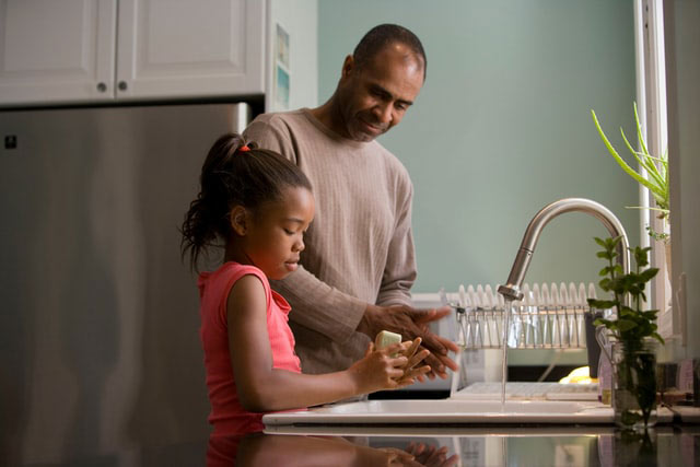 Father teaching daughter how to wash hands