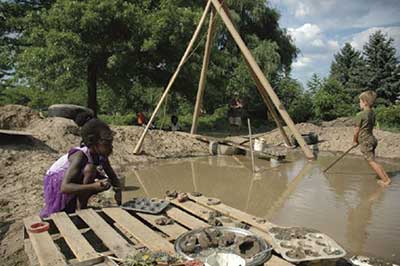 Children playing near home made pond