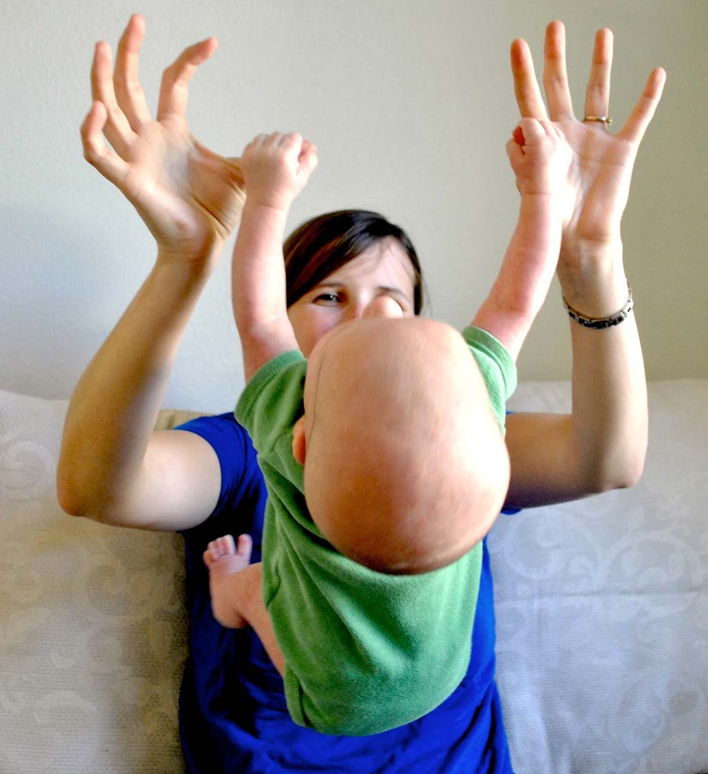 Baby hanging from mother's thumbs