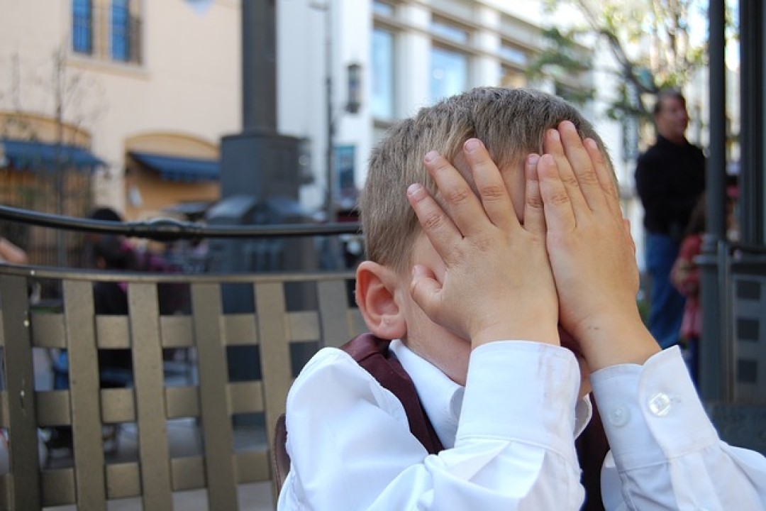 Boy with hands over face.