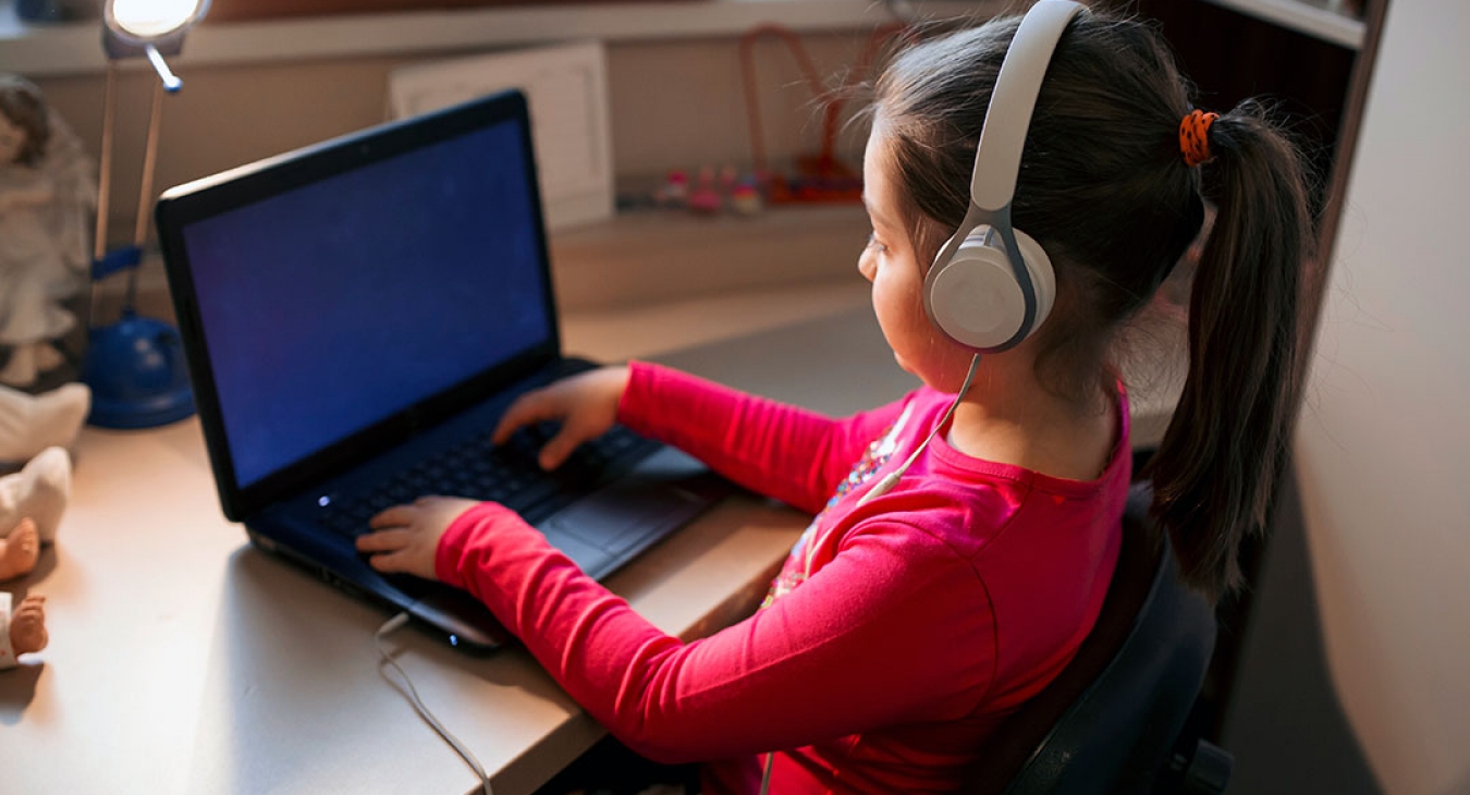 Little girl listening to music while studying on the computer