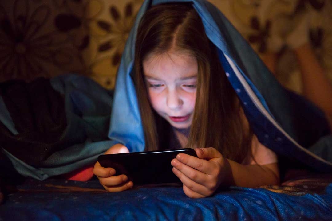 girl playing smartphone game in a dark room
