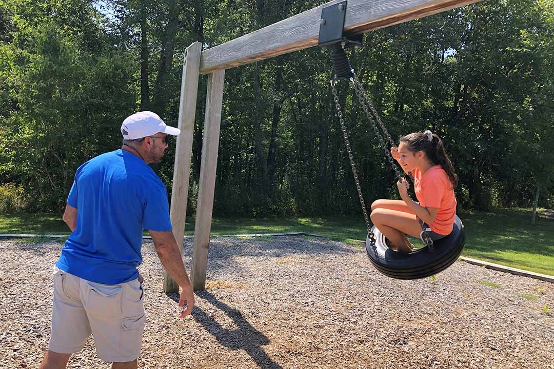 Father pushing daughter on tire swing