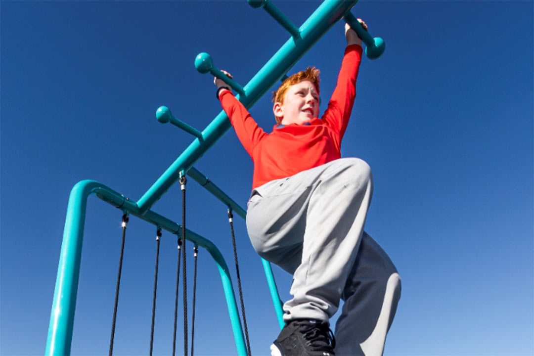 red headed boy crossing the monkey bars