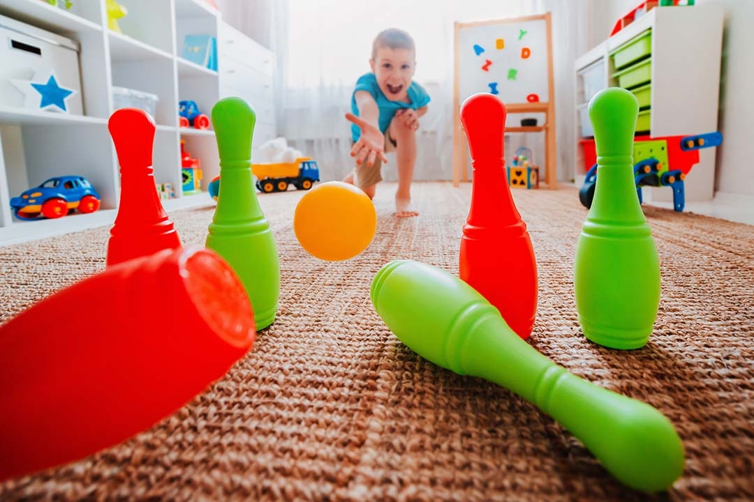 boy throws ball at home bowling toy