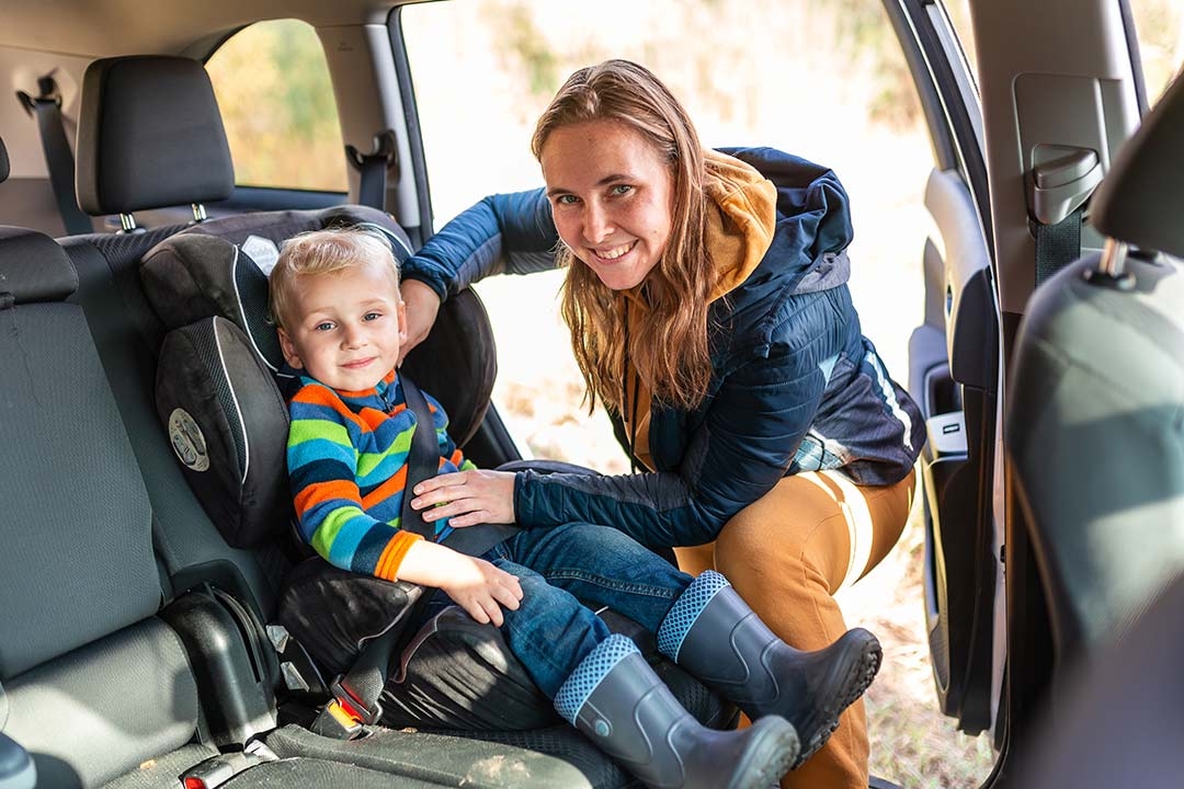 mother buckling her son into a car seat
