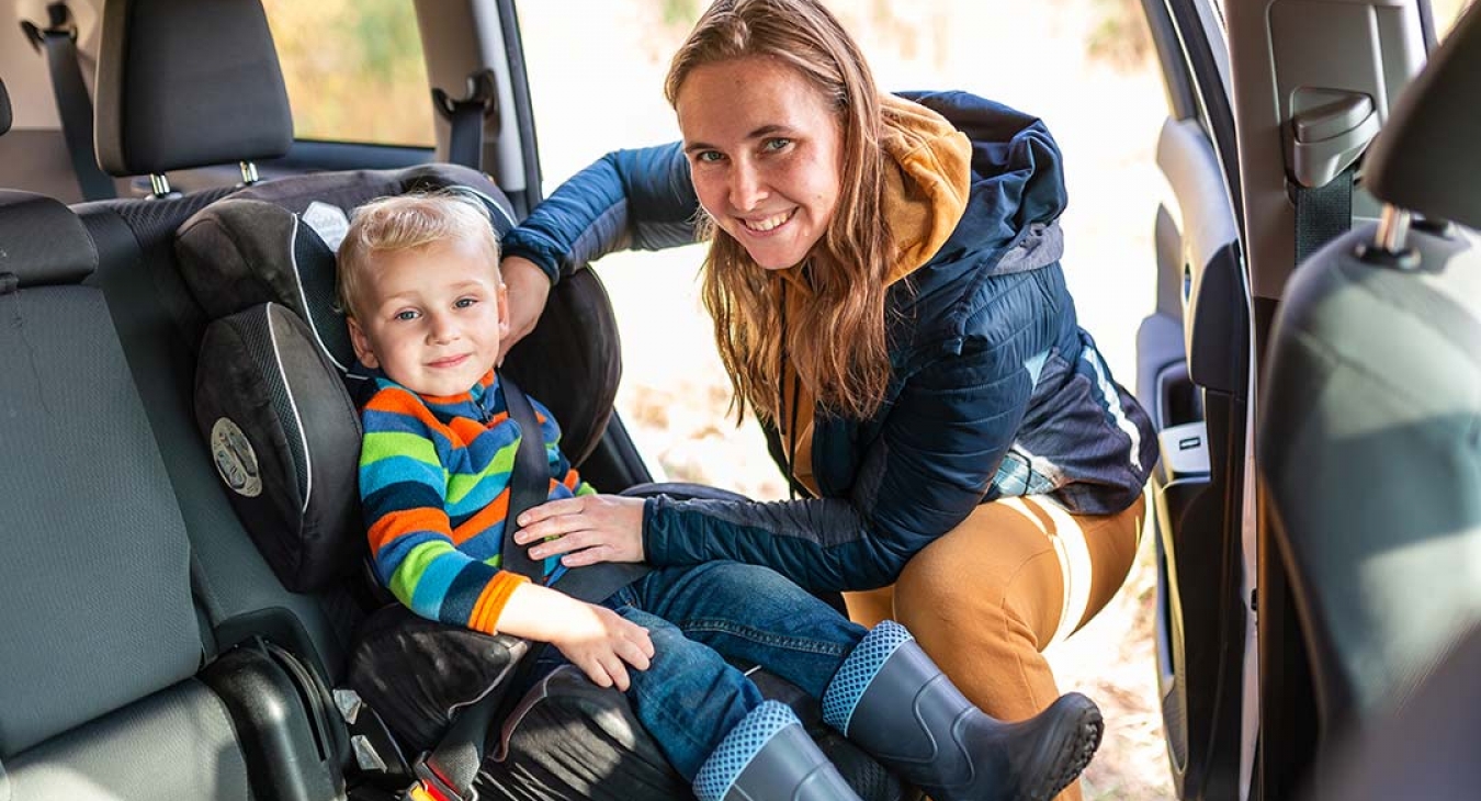 mother buckling her son into a car seat