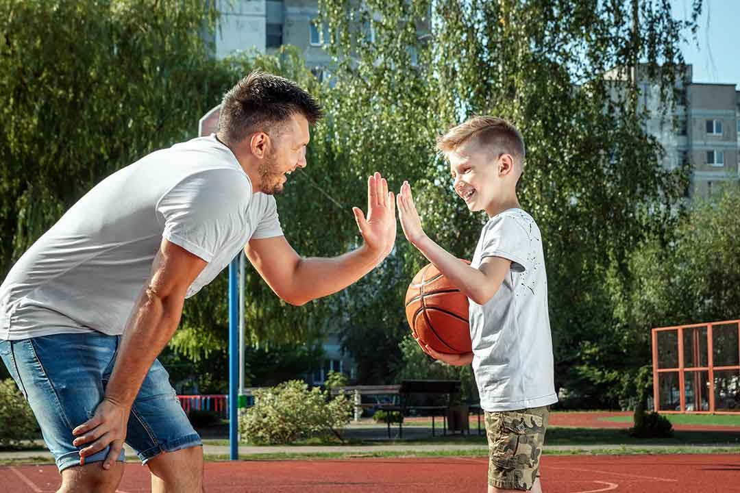Father and son playing basketball together outdoor basketball court