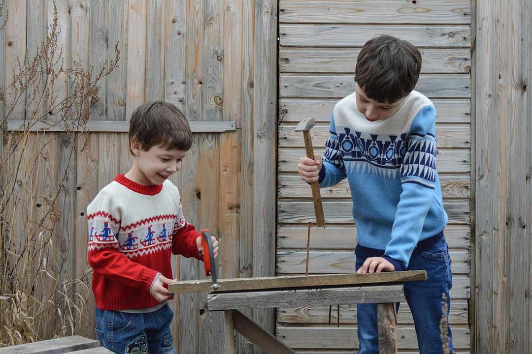 brothers sawing and hammering wood outside