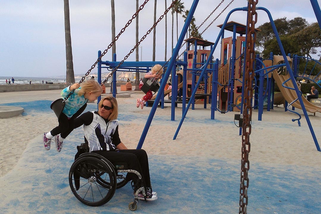 Gold medalist Paralympian, Muffy Davis pushes her daughter on the swings