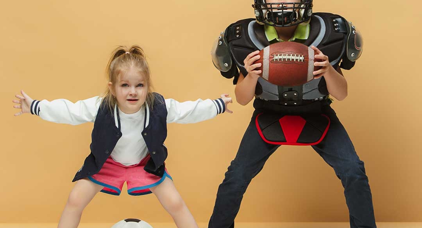 two children, one with soccer ball, one with football/football gear.