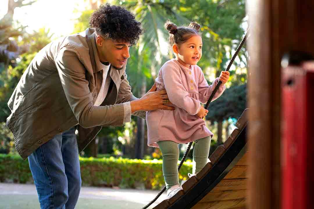 Father helps Daughter on Playground