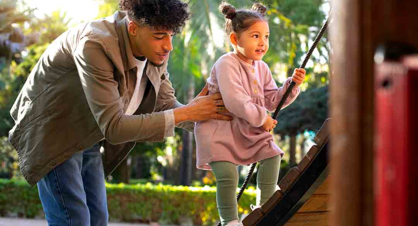 Father helps Daughter on Playground