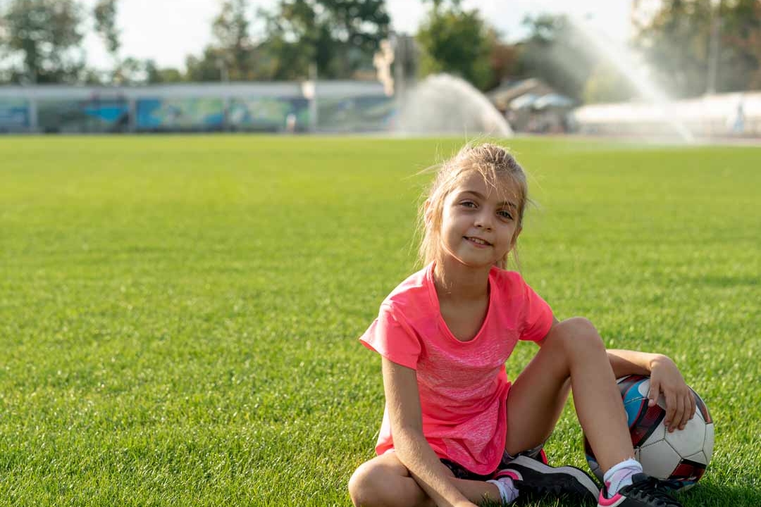Girl in grass with a soccer ball