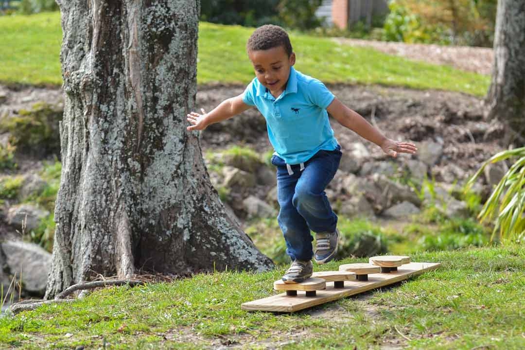 Child balancing on Outdorable natural timber river rock stepping stones outdoors developing gross motor skills and coordination