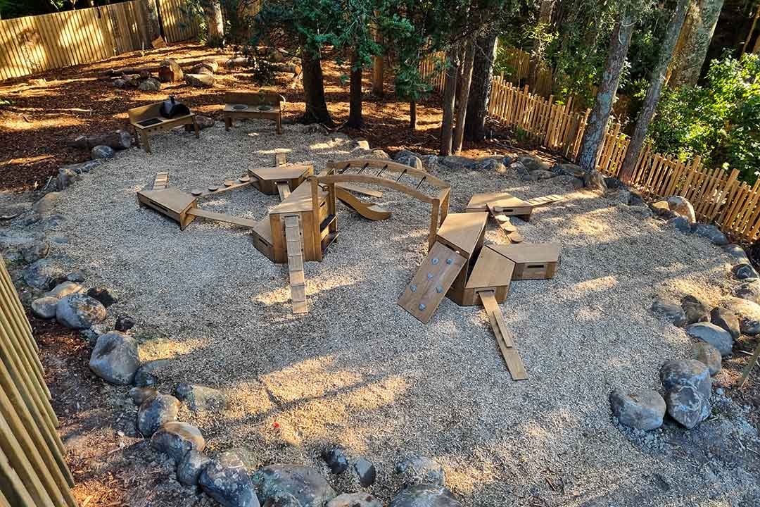 Aerial view of Outdorable configurable timber play equipment arranged in a circular layout with loose fill surfacing and natural rock edging