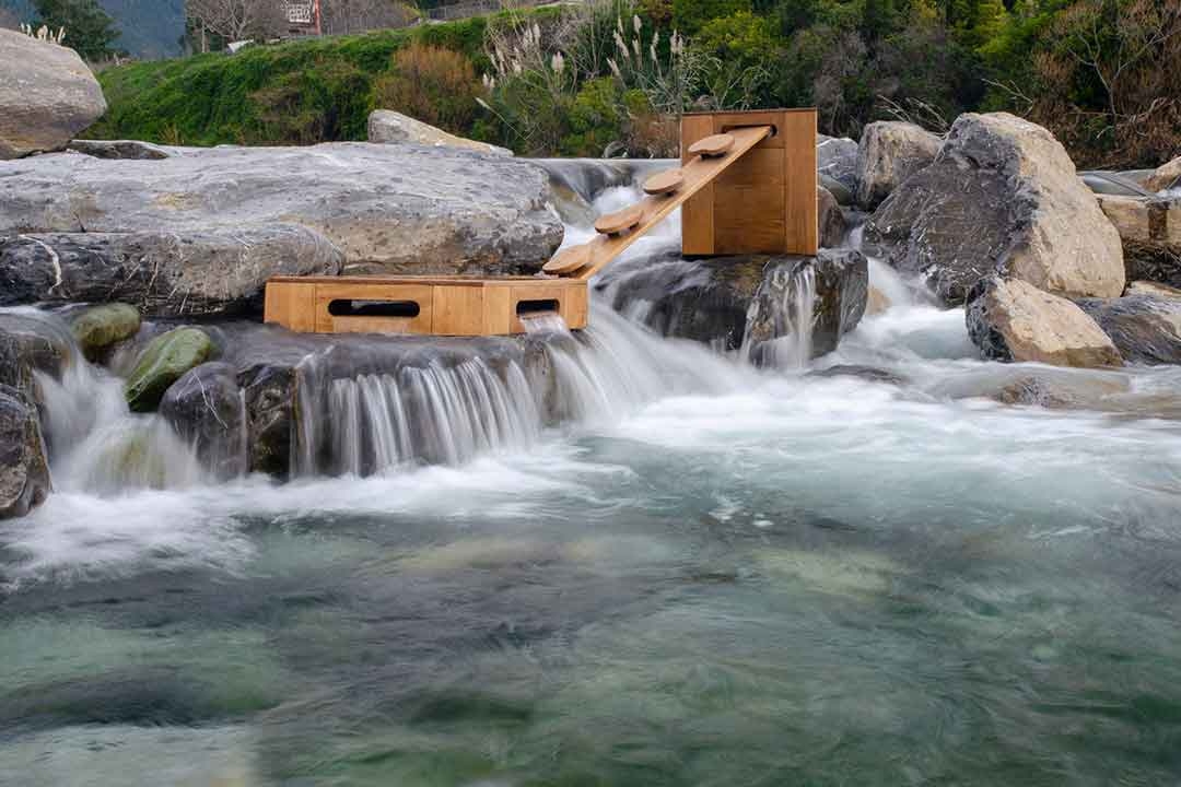 Outdorable sustainable timber play equipment positioned alongside a natural river demonstrating weather-resistant outdoor durability
