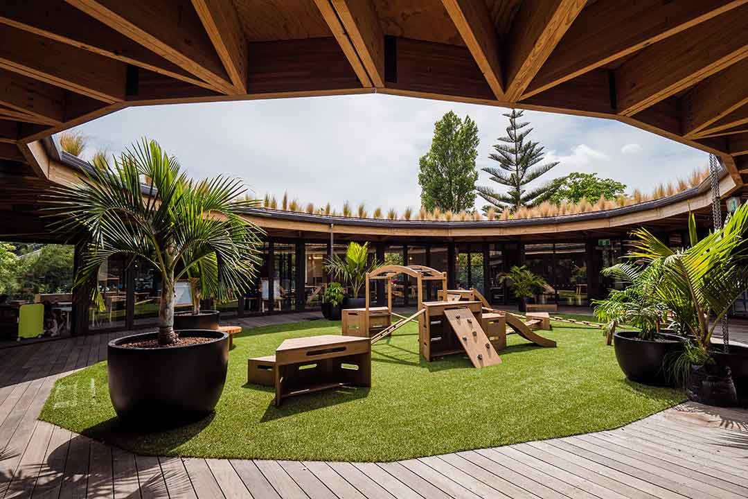 Wide view of Outdorable nature-inspired modular play equipment in a circular open-air early learning centre courtyard with tropical planting
