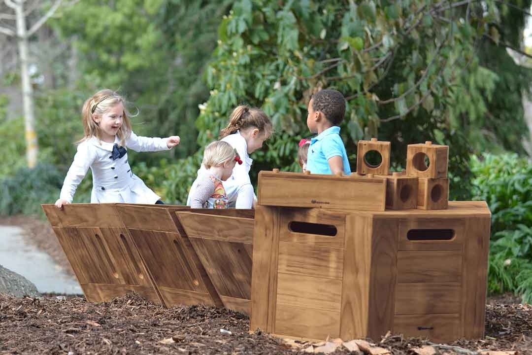 Group of children engaged in imaginative open-ended play on Outdorable modular timber play equipment in a garden setting