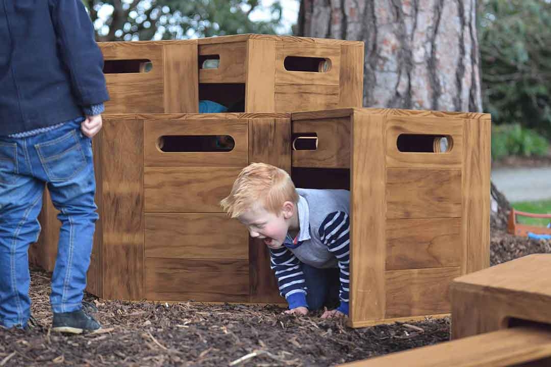 oddler crawling through an Outdorable Beaverlodge timber climber cave encouraging imaginative play and physical exploration