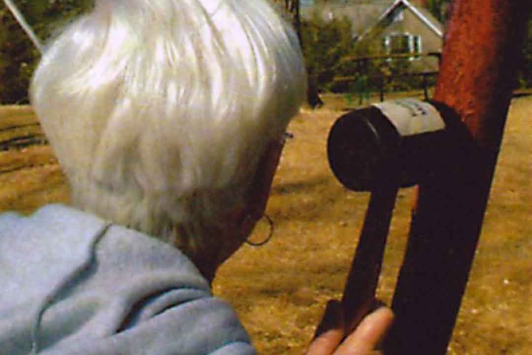 White-haired inspector examining a rusted swing set support beam and hardware connection up close