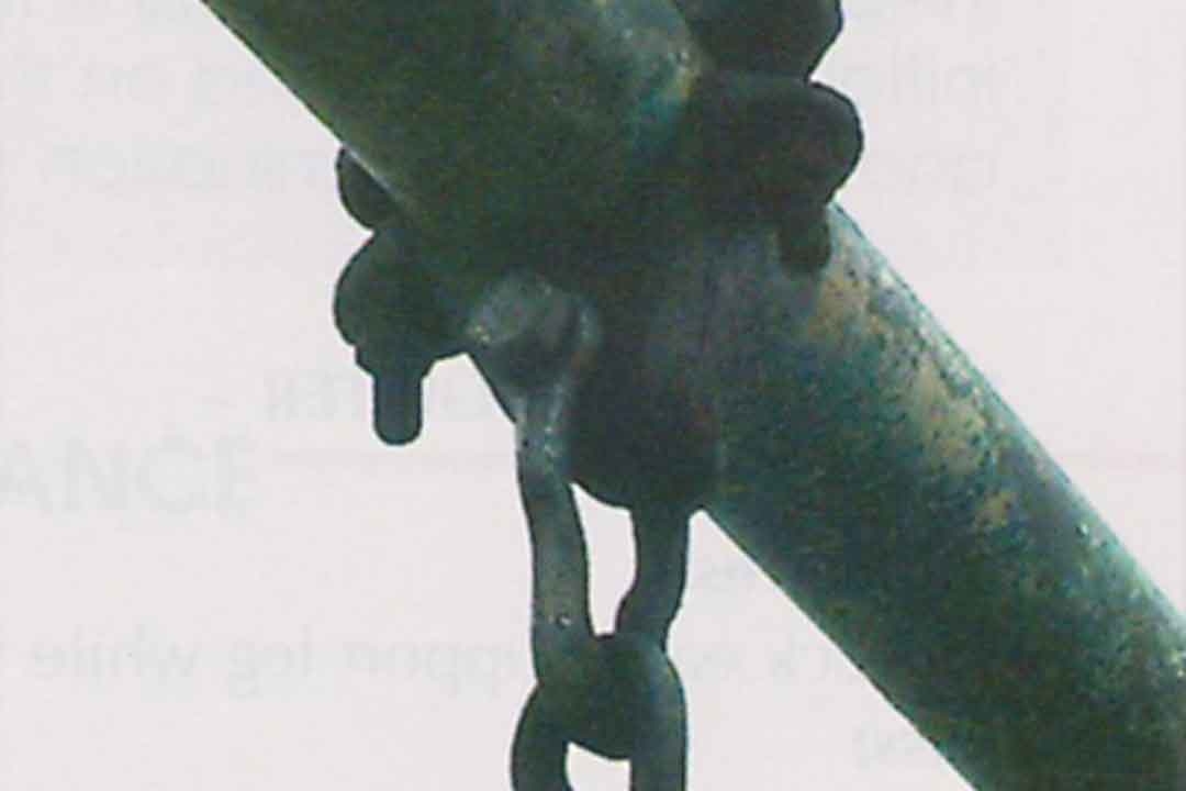 Close-up of a worn swing chain attachment showing corrosion and oxidation on the metal hanger and overhead beam