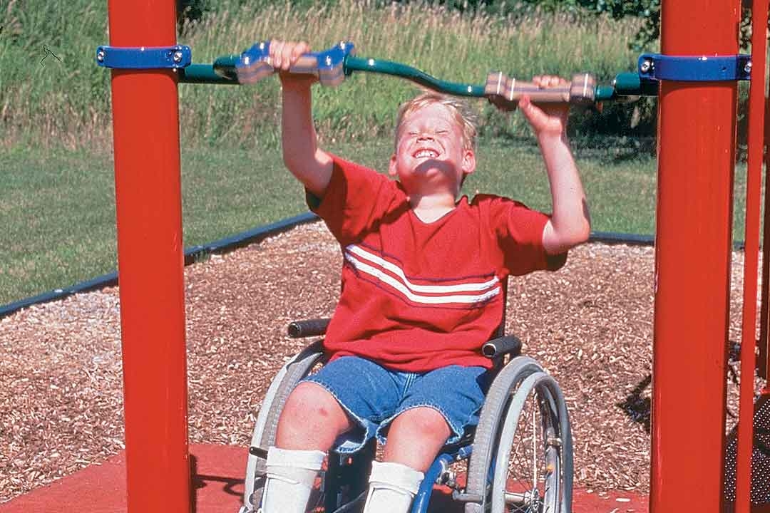 Boy in a wheelchair playing on accessible playground equipment designed for inclusive use