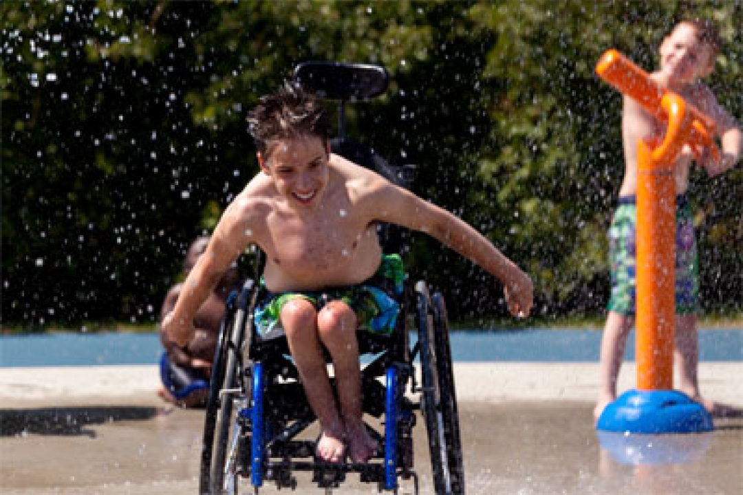 Boy in wheelchair enjoys a splash pad.