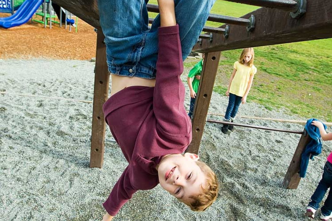 Child hanging from monkey bars.