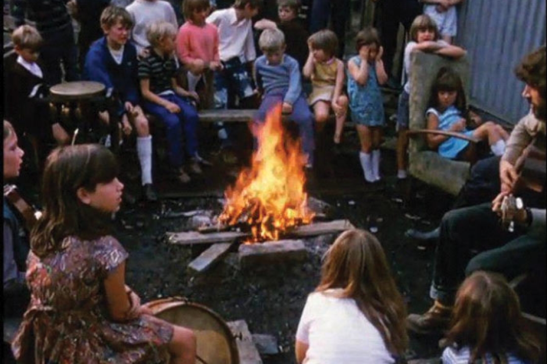 A Play worker hosting kids around a campfire.