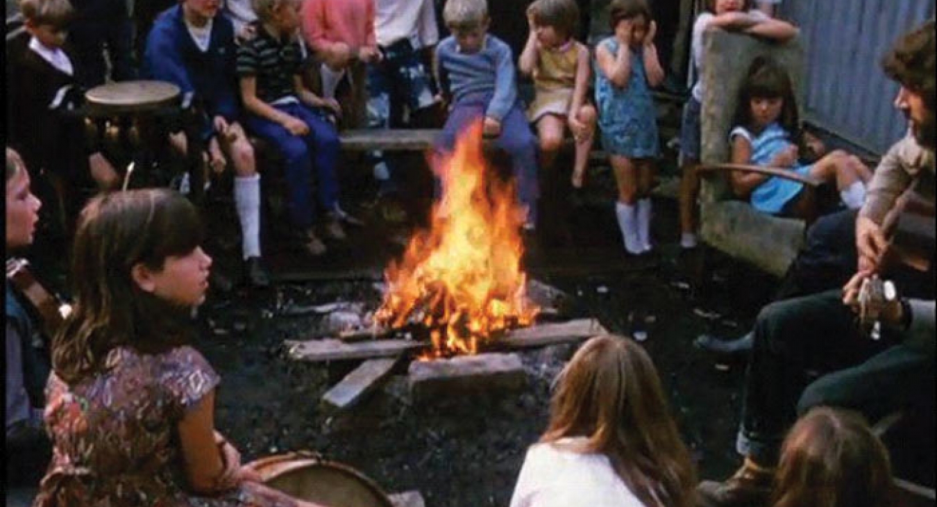 A Play worker hosting kids around a campfire.