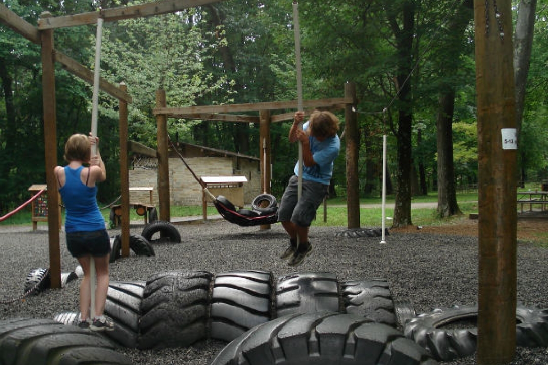Teens playing on a playground made from old tires.