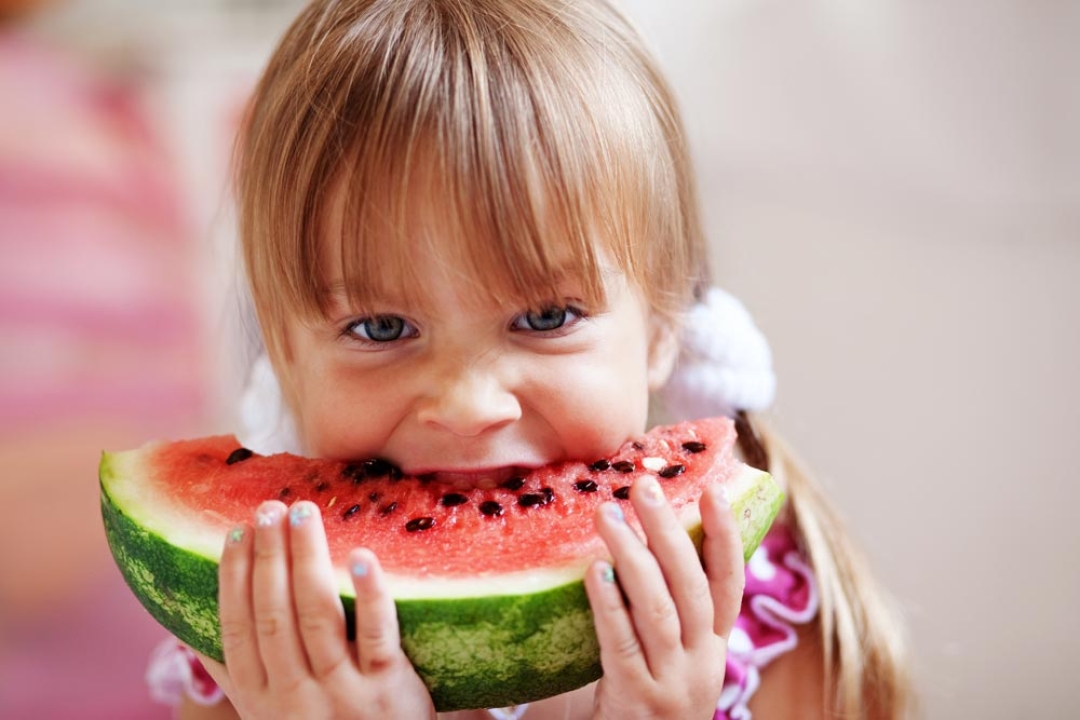 Young girl eating fruit at watermelon