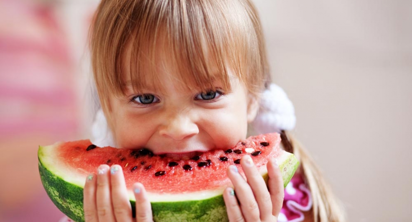 Young girl eating fruit at watermelon