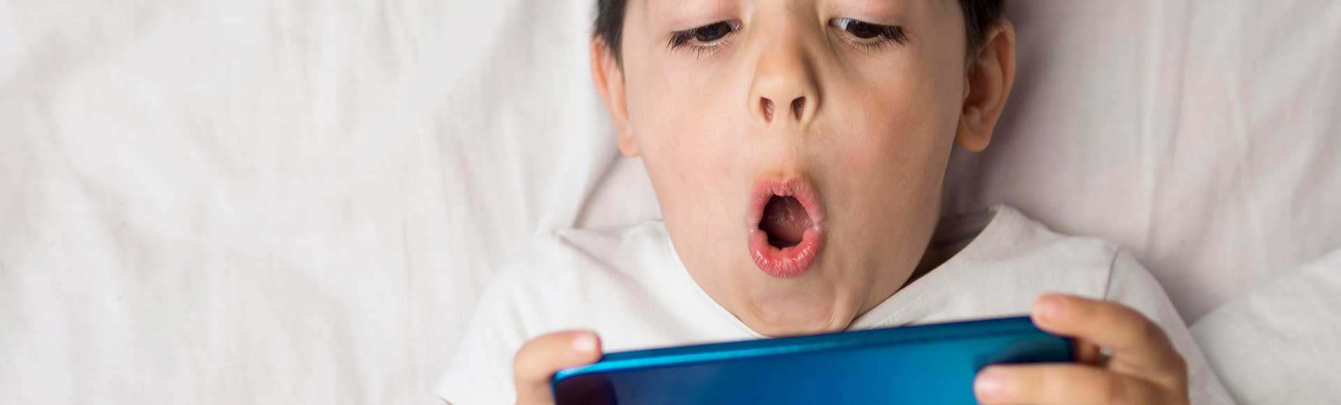 boy laying in bed on phone