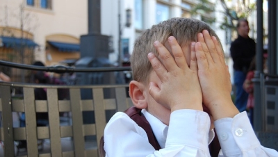 Boy with hands over face.