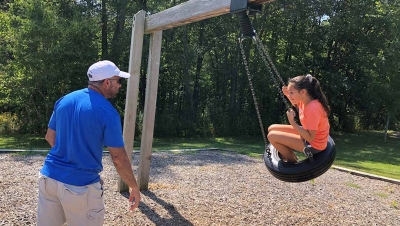 Father pushing daughter on tire swing