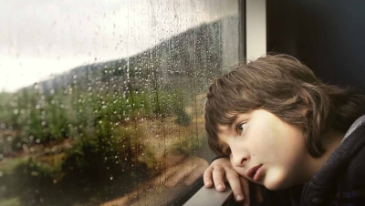Child with ADHD looking outside on a rainy day