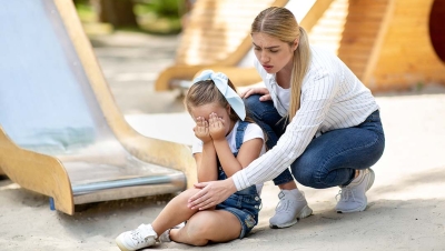 mom comforting her hurt daughter on the playground 