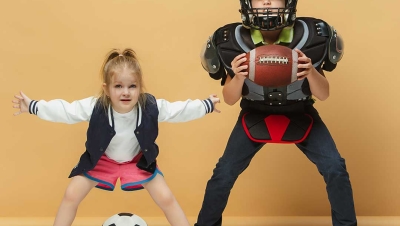 two children, one with soccer ball, one with football/football gear.