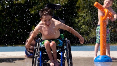 Boy in wheelchair enjoys a splash pad.