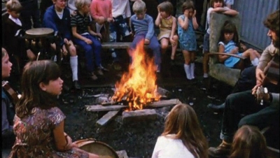 A Play worker hosting kids around a campfire.